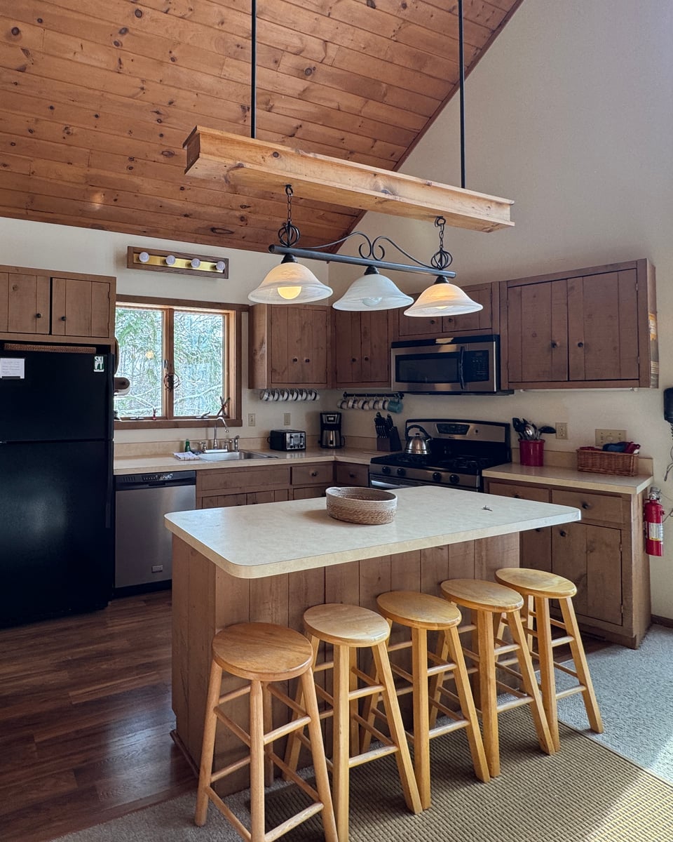 The kitchen island with five wooden stools under pendant lights.